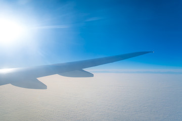 The plane fly in the sky on the background of the bright sun