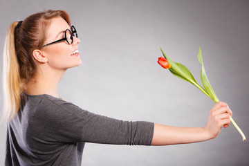 Smiling lady sniffing flower.