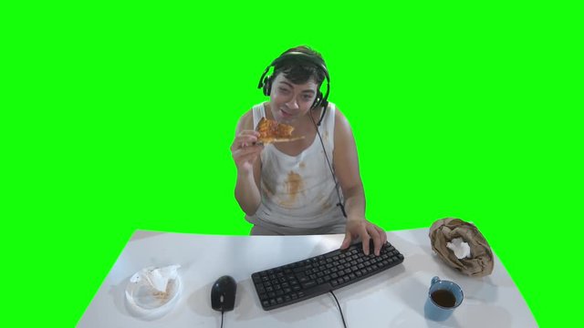 Man in dirty clothes eating pizza while playing on computer