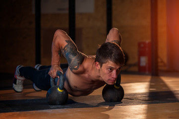 Sporty man doing push up exercise with kettle bell