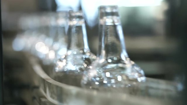 close-up shot of bottles in a row on a conveyor belt. Production of glass bottles