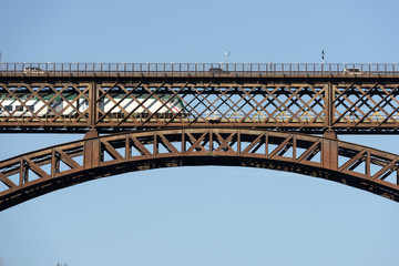 train passes under cars on old iron bridge on  river Adda , shot in bright light at Paderno, Lombardy, Italy. © hal_pand_108