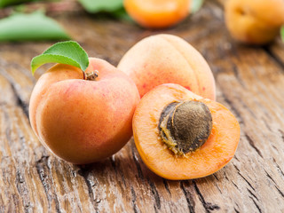 Apricots and its cross-section on the old wooden table.