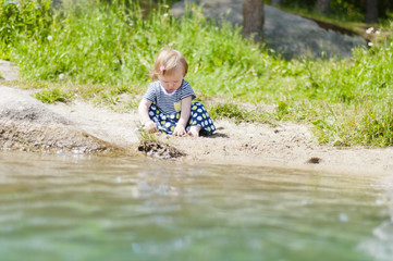 Little girl playing on the river bank
