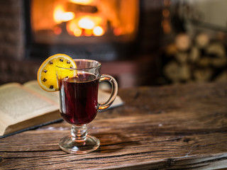 Hot mulled wine and a book on the wooden table.