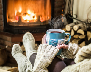 Fototapeta na wymiar Warming and relaxing near fireplace with a cup of hot drink.