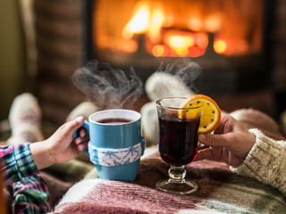 Warming and relaxing near fireplace with a cup of hot drink.
