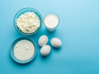Protein products: cheese, cream, milk, eggs on the blue backgrou