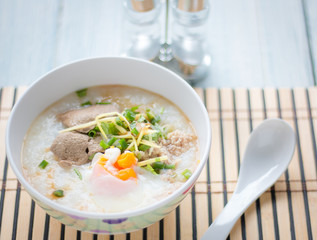 Traditional chinese porridge rice gruel in bowl on white wooden background.