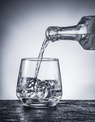 Pouring alcohol into a glass. Monochrome picture.