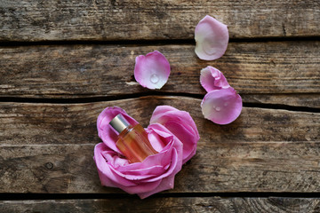 Essential oil with flower petals on wooden background