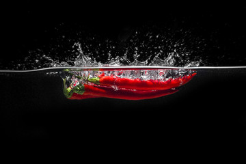 Red hot chili pepper splashing into water