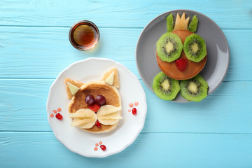 Plates with creative homemade pancakes on wooden table