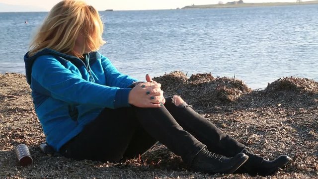 Thoughtful, pensive woman on winter sea beach sitting