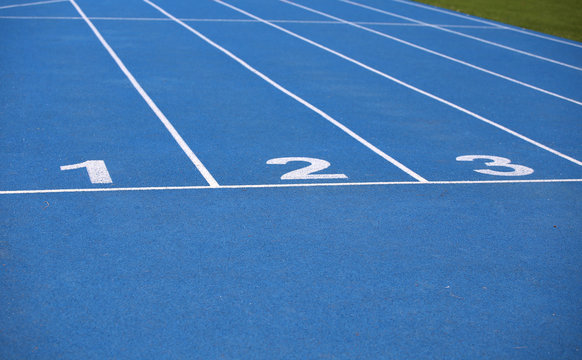 lanes of a blue athletic track with one two and three numbers