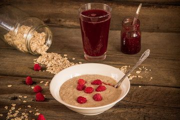 Oatmeal porridge with raspberries and compote on the wooden tabl