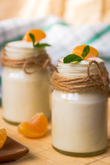 Fresh organig natural white yogurt in glass jars with tangerine