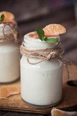 Fresh organig natural white yogurt in glass jars with tangerine