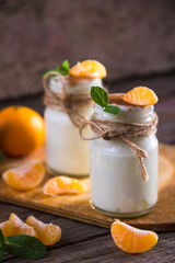 Fresh organig natural white yogurt in glass jars with tangerine