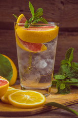 Fresh lemonade in a glass beaker with ice, green mint, red orang