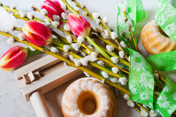 Traditional Czech easter decoration - regional wooden ratchet instrument with homemade cake with pussycats and tulips flower. Spring easter holiday arrangement.