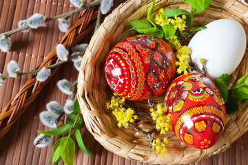 Traditional Czech easter decoration - colorful painted red eggs in wicker nest with pussycats and...