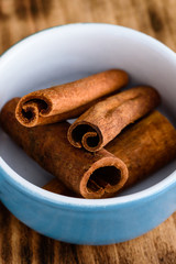 Whole cinnamon inside blue enameled cast iron pot standing om wooden board.