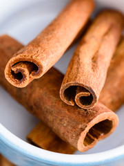 Close up of whole cinnamon sticks inside enameled cast iron pot.