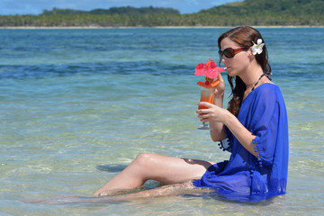 Tourist woman drinks a tropical cocktail in the waters of a reso