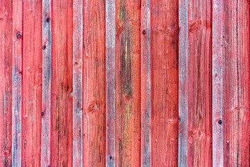 Wood barn wall with red peeling flaking color. Red wooden background texture.