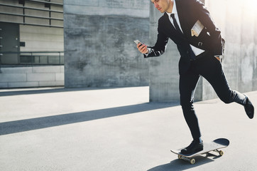 Stylish businessman does skating while holding phone
