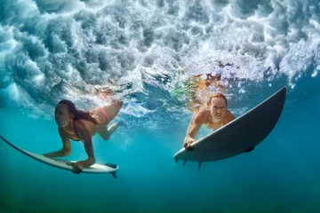 Poster Group of active girls in action. Surfer women with surf board dive underwater under breaking big wave. Healthy lifestyle. Water sport, extreme surfing in adventure camp on family summer beach vacation © Tropical studio