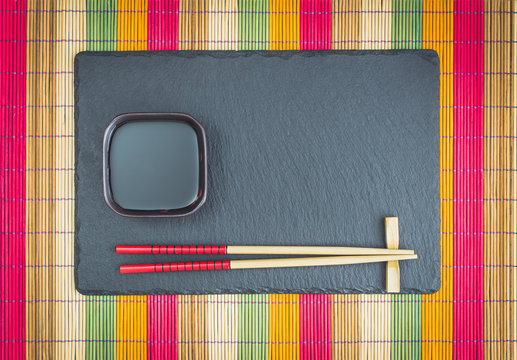 Chopsticks  and soy sauce on slate top view
