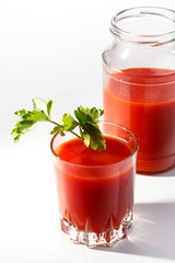 Tomato juice is poured from the glass jar into a glass.