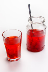 Cherry compote in a jar in a glass on a white background.