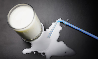 glass of milk splashing and tube straw on table