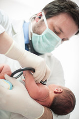 Pediatrician holding a newborn baby boy in hospital