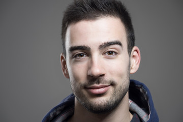 Obraz premium Close up horizontal portrait of young unshaven man wearing hoodie looking at camera