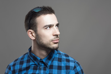 Annoyed young man with sunglasses in hair looking up at copyspace 