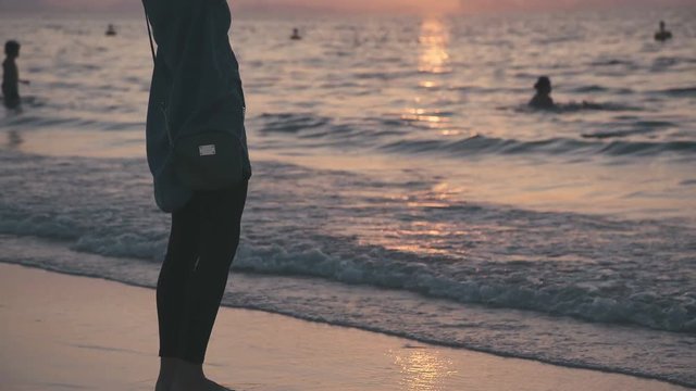 Silhouette of a slender girl: a woman makes selfi on the Persian Gulf at sunset. Woman photographed themselves on the phone: sunset sky, the silhouette of the hotel in the form of Sail away.