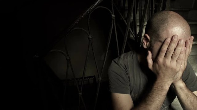 bald man desperately holding his face in hands