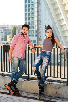 Couple on rollerblades outdoor. People standing on city background. Young, bold and stylish.