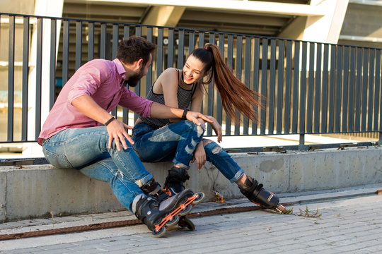 Couple on rollerblades is sitting. Young woman laughing. Great idea for first date.