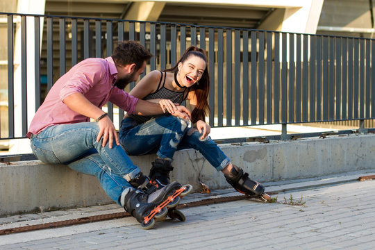 Two people on rollerblades sitting. Young female laughing. Funny things that you say.