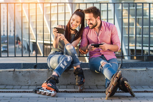 Man and woman with phones. Girl on inline skates smiling. Posting photos on the internet.