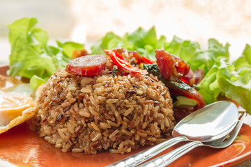 Closeup view of spicy basil thai food, black, brown rice with pork sausage and fried egg.
