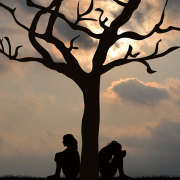 Silhouette of sad women sitting under the tree