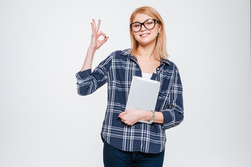 Happy woman holding tablet and make okay gesture