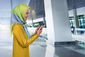 Pretty asian muslim woman touching her mobile phone