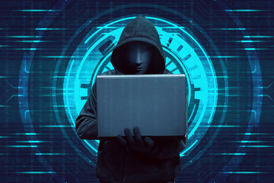 Hooded hacker typing on laptop while standing